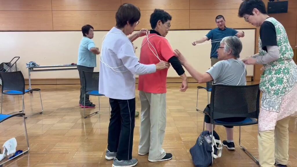 参加者同士で、体を締めつけないように紐を身につける様子